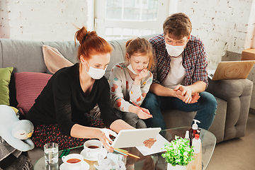 Image showing Caucasian family in protective masks and gloves isolated at home with coronavirus symptoms, treatment