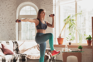 Image showing Young woman teaching at home online courses of fitness, aerobic, sporty lifestyle while being quarantine