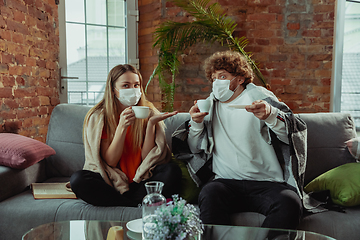 Image showing Woman and man, couple in protective masks and gloves isolated at home with coronavirus symptoms