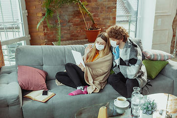 Image showing Woman and man, couple in protective masks and gloves isolated at home with coronavirus symptoms