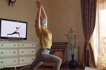 Image showing Sporty young woman taking yoga lessons online and practice at home while being quarantine