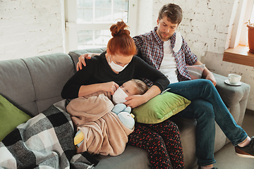 Image showing Caucasian family in protective masks and gloves isolated at home with coronavirus symptoms, treatment