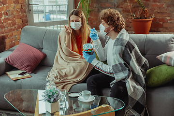 Image showing Woman and man, couple in protective masks and gloves isolated at home with coronavirus symptoms