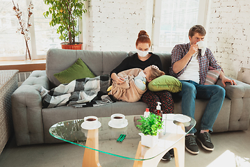 Image showing Caucasian family in protective masks and gloves isolated at home with coronavirus symptoms, treatment