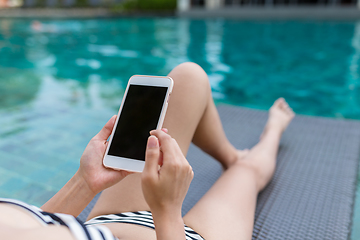 Image showing Woman enjoy sun bath and using mobile phone in swimming pool