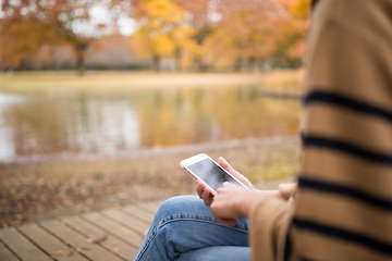 Image showing Woman using cellphone in park at Autumn season