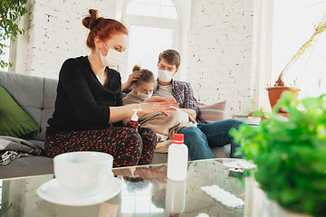 Image showing Caucasian family in protective masks and gloves isolated at home with coronavirus symptoms, treatment