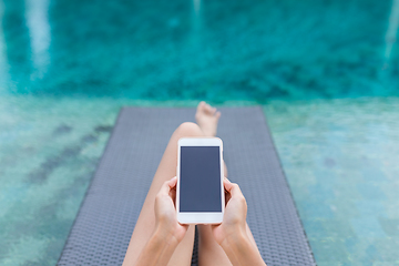 Image showing Woman working on mobile phone at poolside on holiday