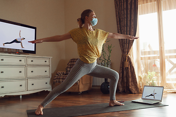 Image showing Sporty young woman taking yoga lessons online and practice at home while being quarantine