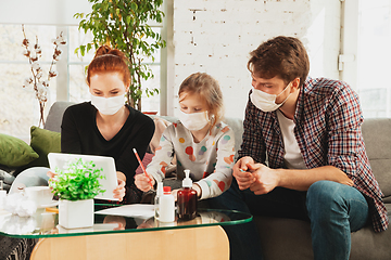 Image showing Caucasian family in protective masks and gloves isolated at home with coronavirus symptoms, treatment