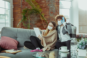 Image showing Woman and man, couple in protective masks and gloves isolated at home with coronavirus symptoms