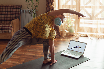 Image showing Sporty young woman taking yoga lessons online and practice at home while being quarantine