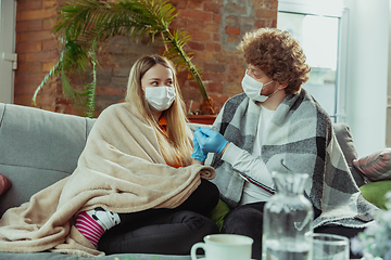 Image showing Woman and man, couple in protective masks and gloves isolated at home with coronavirus symptoms