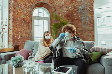 Image showing Woman and man, couple in protective masks and gloves isolated at home with coronavirus symptoms