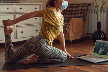 Image showing Sporty young woman taking yoga lessons online and practice at home while being quarantine