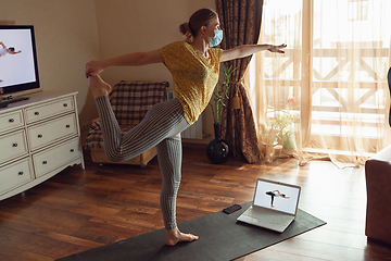 Image showing Sporty young woman taking yoga lessons online and practice at home while being quarantine