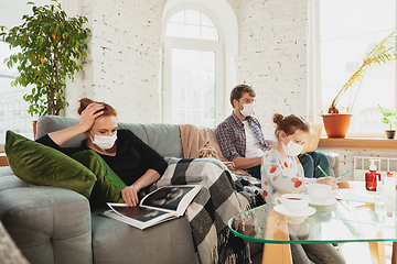 Image showing Caucasian family in protective masks and gloves isolated at home with coronavirus symptoms, treatment