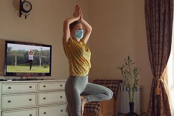 Image showing Sporty young woman taking yoga lessons online and practice at home while being quarantine