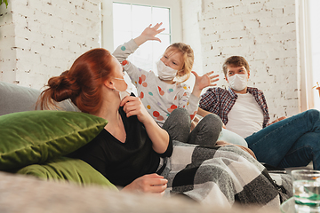 Image showing Caucasian family in protective masks and gloves isolated at home with coronavirus symptoms, treatment