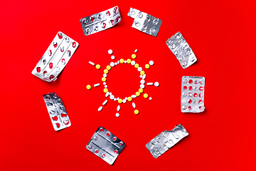 Image showing Colored pills, tablets and capsules on a red background - history of treatment, prevention of pandemic