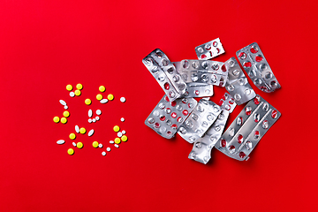 Image showing Colored pills, tablets and capsules on a red background - history of treatment, prevention of pandemic