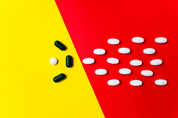 Image showing Colored pills, tablets and capsules on a red and yellow background - history of treatment, prevention of pandemic