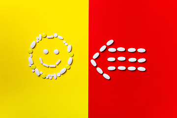 Image showing Colored pills, tablets and capsules on a red and yellow background - history of treatment, prevention of pandemic