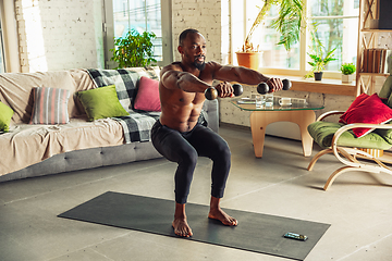 Image showing Young african-american man teaching at home online courses of fitness, aerobic, sporty lifestyle while being quarantine