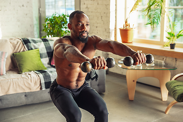 Image showing Young african-american man teaching at home online courses of fitness, aerobic, sporty lifestyle while being quarantine