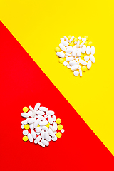 Image showing Colored pills, tablets and capsules on a red and yellow background - history of treatment, prevention of pandemic