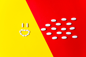 Image showing Colored pills, tablets and capsules on a red and yellow background - history of treatment, prevention of pandemic