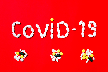 Image showing Colored pills, tablets and capsules on a red background - history of treatment, prevention of pandemic