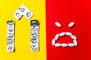 Image showing Colored pills, tablets and capsules on a red and yellow background - history of treatment, prevention of pandemic