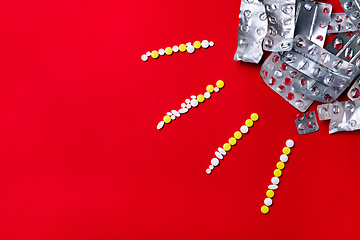 Image showing Colored pills, tablets and capsules on a red background - history of treatment, prevention of pandemic