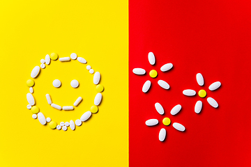 Image showing Colored pills, tablets and capsules on a red and yellow background - history of treatment, prevention of pandemic