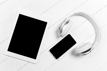 Image showing Tablet and headphones. Monochrome stylish composition in white color. Top view, flat lay.