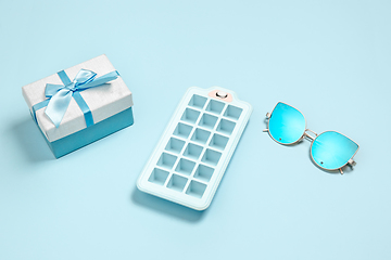 Image showing Gift, present box, ice form and eyeglasses. Monochrome stylish composition in blue color. Top view, flat lay.