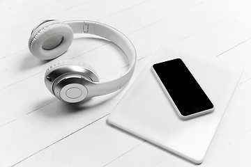 Image showing Smartphone and headphones. Monochrome stylish composition in white color. Top view, flat lay.