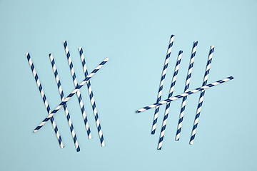 Image showing Straws with strips. Monochrome stylish composition in blue color. Top view, flat lay.