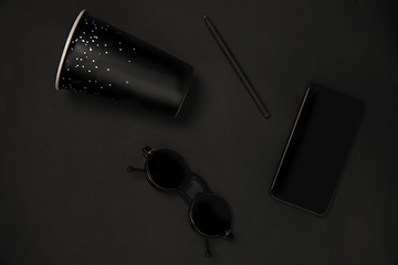 Image showing Gadget, coffee and eyewear. Monochrome stylish composition in black color. Top view, flat lay.