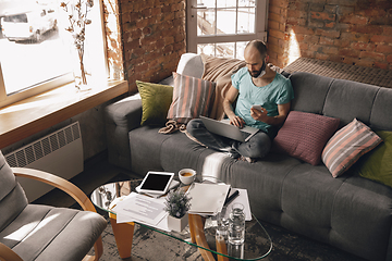 Image showing Young man doing yoga at home while being quarantine and freelance working