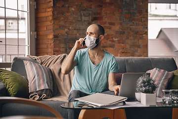 Image showing Young man doing yoga at home while being quarantine and freelance working