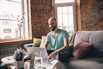 Image showing Young man doing yoga at home while being quarantine and freelance working