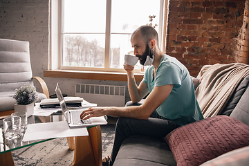 Image showing Young man doing yoga at home while being quarantine and freelance working