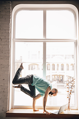 Image showing Young man doing yoga at home while being quarantine and freelance working