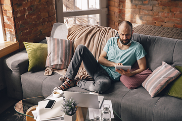 Image showing Young man doing yoga at home while being quarantine and freelance working