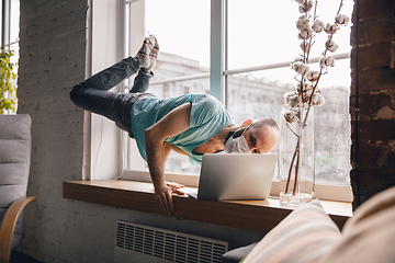 Image showing Young man doing yoga at home while being quarantine and freelance working