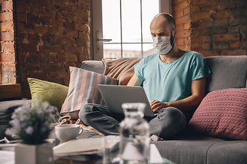 Image showing Young man doing yoga at home while being quarantine and freelance working