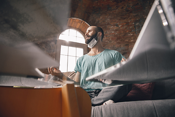 Image showing Young man doing yoga at home while being quarantine and freelance working