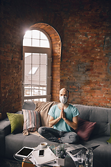 Image showing Young man doing yoga at home while being quarantine and freelance working